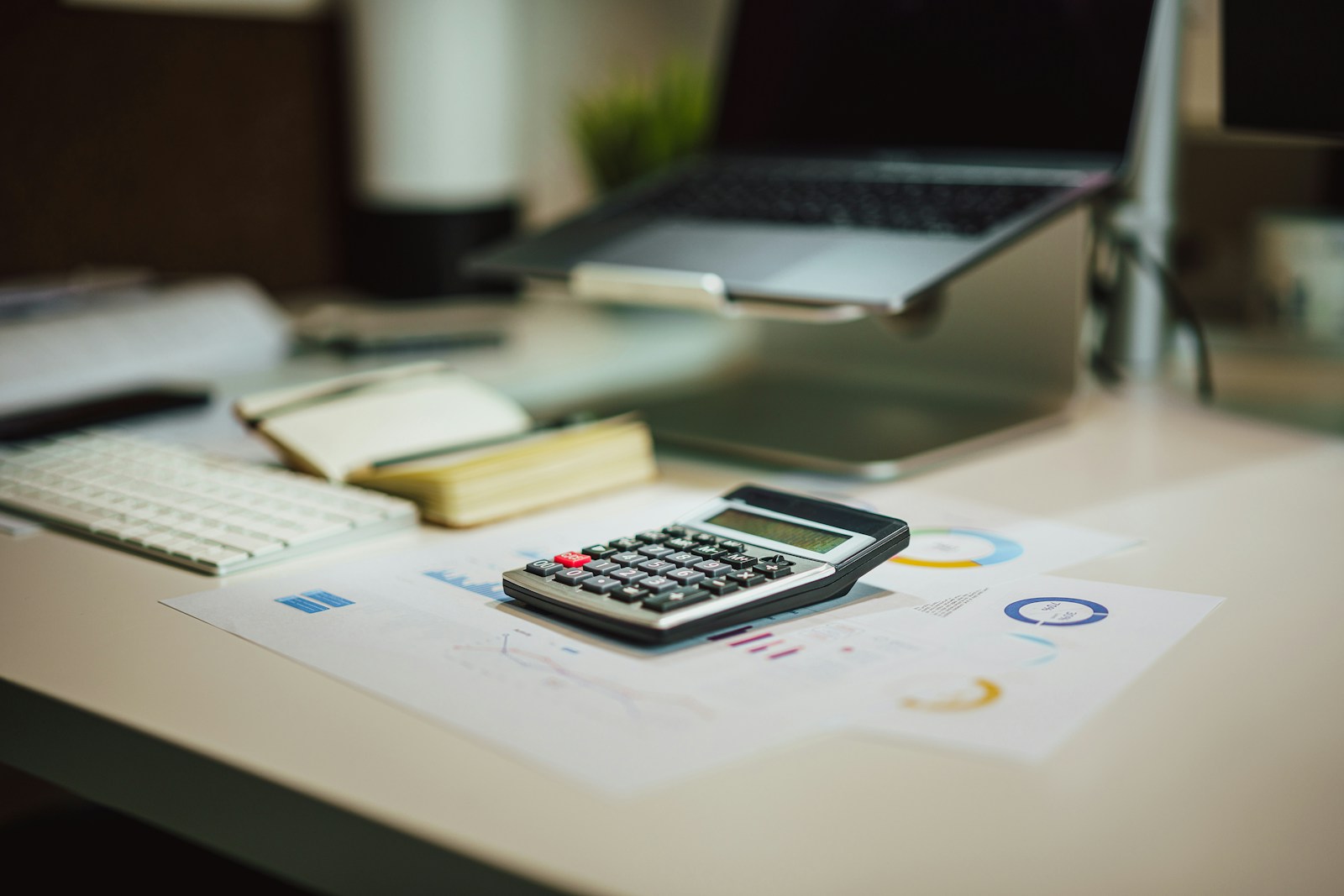 Calculator resting on financial reports and charts on an office desk